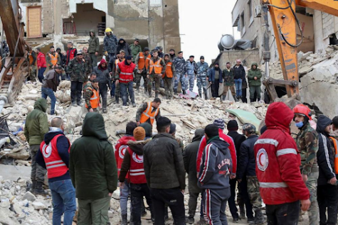 Rescuers search for survivors at the site of a collapsed building– Hama, Syria