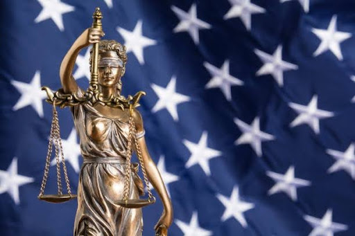 This photo shows the stars of the United States flag in the background with the statue of Lady Justice